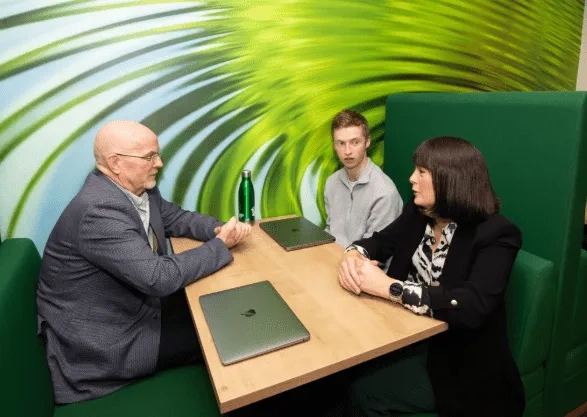 group of 3 at work desk, talking.