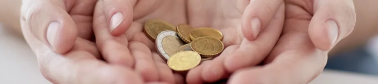 Two hands cupping a collection of coins, symbolizing charitable giving or fundraising.