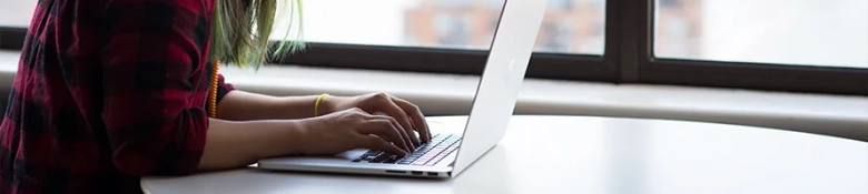 Woman wearing headphones writes her CV on a laptop