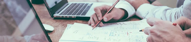 Two people working on laptops and with pen and paper