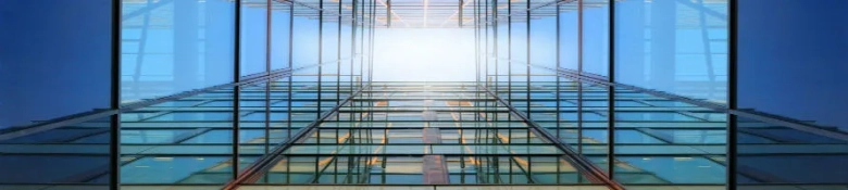 Symmetrical view looking up the facade of a modern glass building against a clear sky.