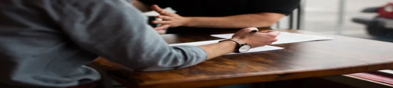 Two individuals discussing documents on a wooden table, possibly exploring study abroad options.