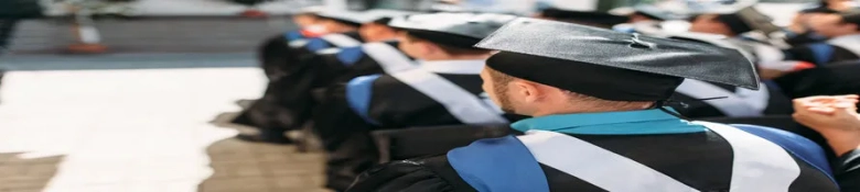 Graduates in ceremonial attire sitting in a row during a graduation ceremony.