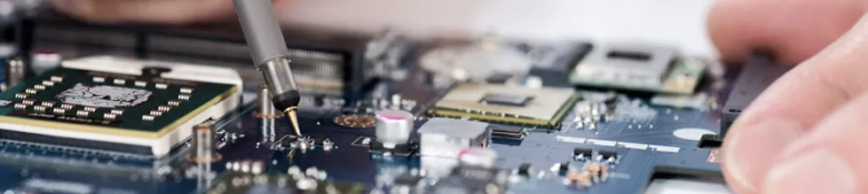 Close-up of a technician's hand soldering components on a circuit board.