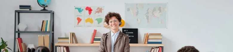 Young teacher stands smiling at the front of a class of young children